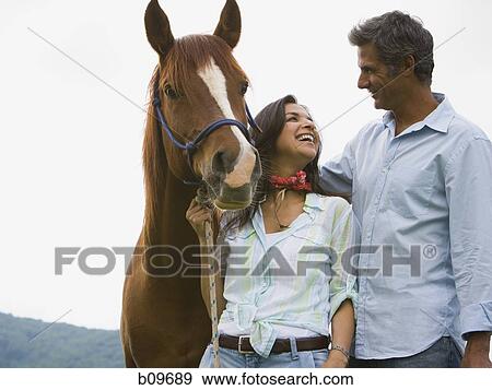woman holding the reins of a horse with a man beside her View Large Photo Image Stock Photo - woman holding the reins of a horse with a man beside her. Fotosearch