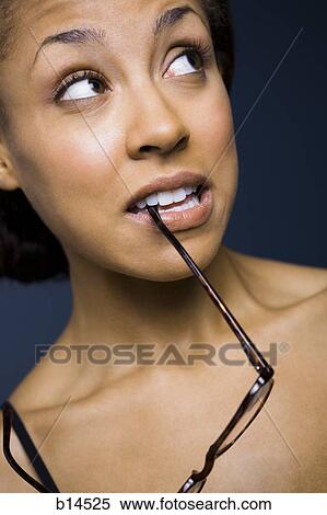 Woman looking up biting arm of eyeglasses View Large Photo Image Stock Photography - Woman looking up biting arm of eyeglasses. Fotosearch
