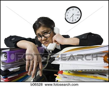 Stock Photo - Woman on telephone with stack of binders. Fotosearch