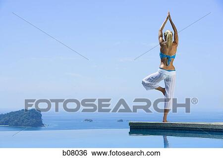 Woman performng yoga exercises by infinity pool View Large Photo Image Stock Photograph - Woman performng yoga exercises by infinity pool. Fotosearch