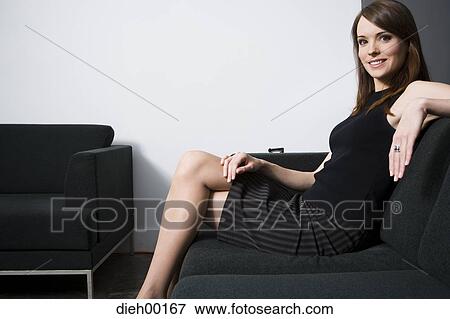 Stock Photo - Woman posing and sitting on a couch. Fotosearch