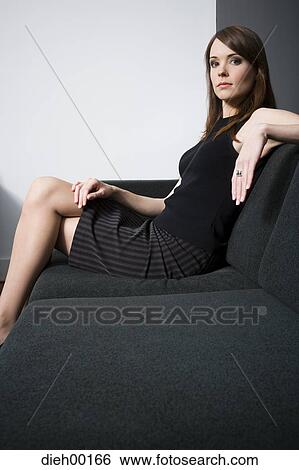 Woman posing and sitting on a couch View Large Photo Image Stock Photograph - Woman posing and sitting on a couch. Fotosearch