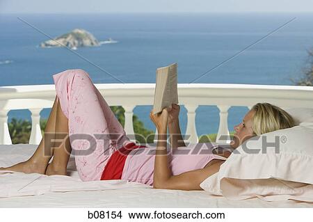 Woman relaxing and reading on balcony overlooking ocean View Large Photo Image Picture - Woman relaxing and reading on balcony overlooking ocean. Fotosearch
