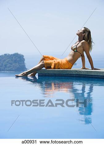 Woman relaxing by infinity pool View Large Photo Image Stock Image - Woman relaxing by infinity pool. Fotosearch