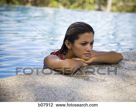 Stock Image - Woman resting on ledge of swimming pool. Fotosearch