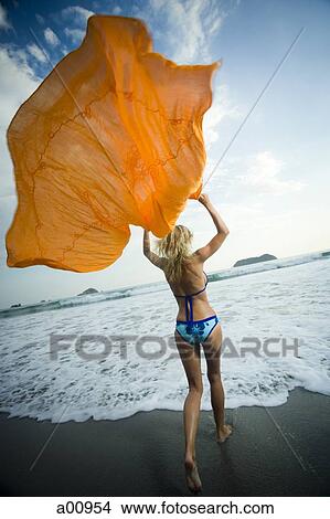 Woman running on beach while holding a shawl View Large Photo Image Picture - Woman running on beach while holding a shawl. Fotosearch