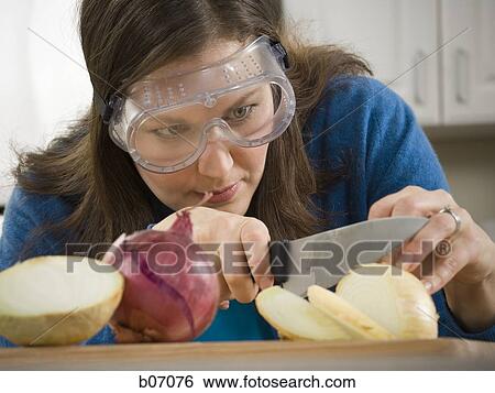 Stock Photograph - Woman slicing onion with saftey goggles. Fotosearch