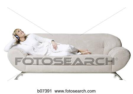 Woman smiling resting on couch with headphones View Large Photo Image Stock Image - Woman smiling resting on couch with headphones. Fotosearch