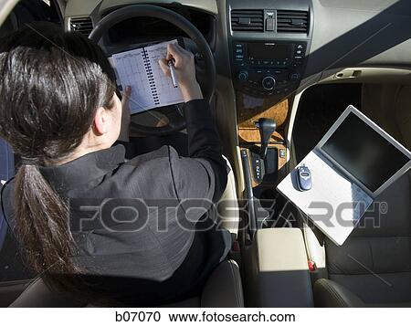 Woman taking notes in car View Large Photo Image Stock Image - Woman taking notes in car. Fotosearch