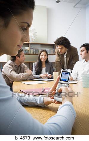 Woman with cell phone at boardroom table with coworkers View Large Photo Image Stock Image - Woman with cell phone at boardroom table with coworkers. Fotosearch
