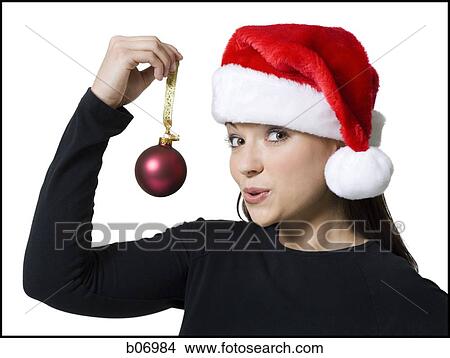 Picture - Woman with christmas ornament and santa hat. Fotosearch