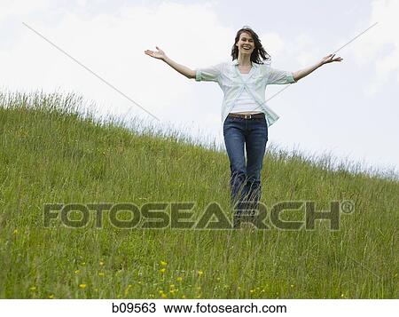 Stock Image - woman with her arms outstretched in a field. Fotosearch