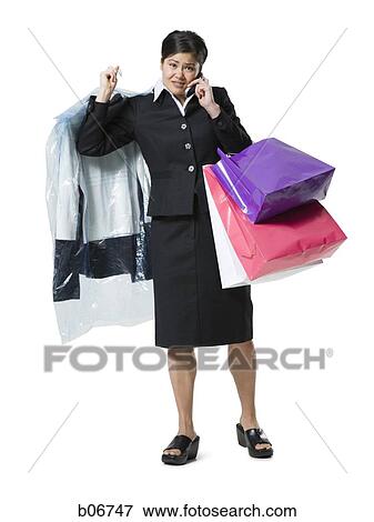 Woman with shopping bags talking on cellphone View Large Photo Image Stock Photo - Woman with shopping bags talking on cellphone. Fotosearch