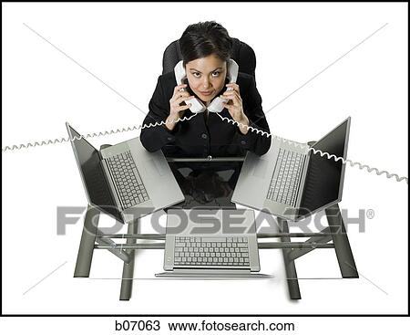 Stock Image - Woman with three laptops and telephone on each ear. Fotosearch