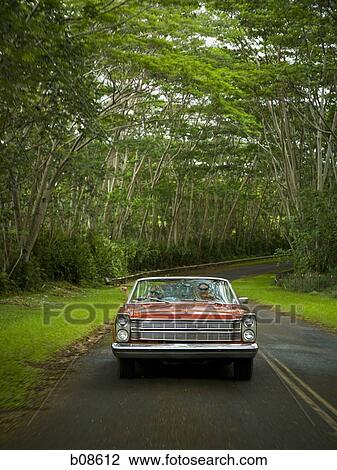 Stock Image - Young couple driving a car on the road. Fotosearch