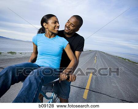 Young couple sitting on a bicycle View Large Photo Image Stock Photo - Young couple sitting on a bicycle. Fotosearch