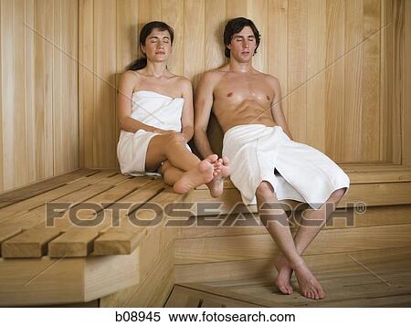 Stock Photography - Young couple sitting on a wooden bench in a sauna. Fotosearch