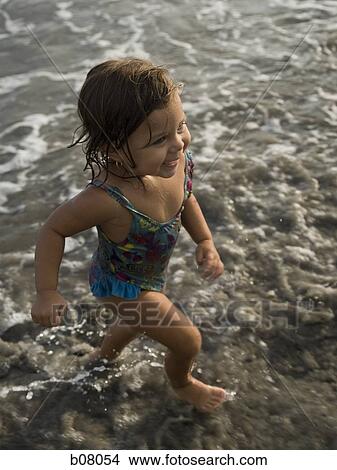Young girl playing in shallow surf on beach View Large Photo Image Picture - Young girl playing in shallow surf on beach. Fotosearch