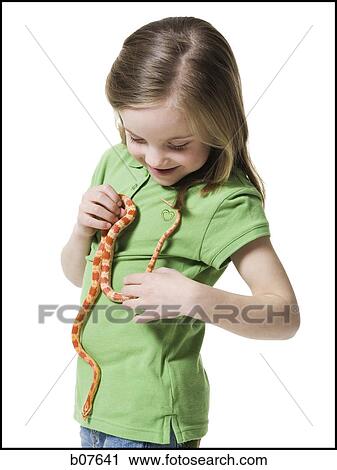 Stock Image - Young girl playing with a snake. Fotosearch