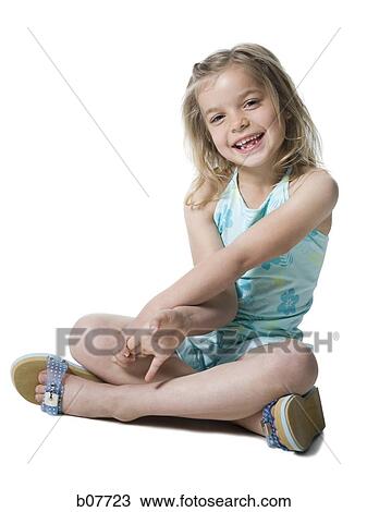 Stock Image - Young girl posing and sitting cross legged. Fotosearch