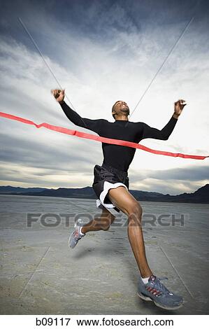 Young man crossing the finish line with his arms raised View Large Photo Image Stock Photo - Young man crossing the finish line with his arms raised. Fotosearch