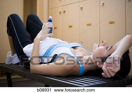 Young woman holding a water bottle and lying on a bench View Large Photo Image Stock Image - Young woman holding a water bottle and lying on a bench. Fotosearch