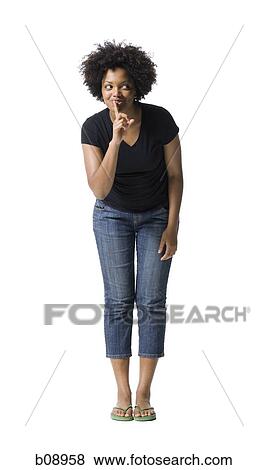 Stock Photo - Young woman standing with her finger on her lips. Fotosearch