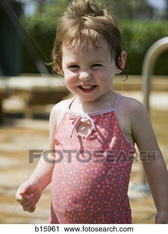 Stock Image - Baby girl standing and smiling outdoors. Fotosearch