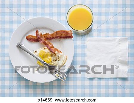 Bacon and eggs with orange juice fork and napkin View Large Photo Image Stock Photo - Bacon and eggs with orange juice fork and napkin. Fotosearch