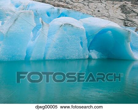 Stock Photography - Blue iceberg in water with rocks. Fotosearch