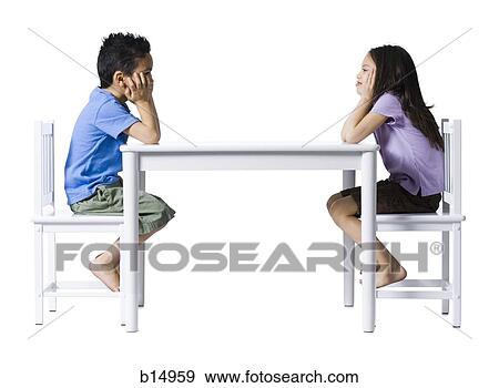 Boy and girl sitting at table with hands on faces View Large Photo Image Stock Photo - Boy and girl sitting at table with hands on faces. Fotosearch