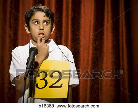 Stock Photo - Boy contestant standing at microphone thinking. Fotosearch