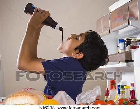 Boy drinking chocolate syrup from bottle in refrigerator View Large Photo Image Stock Photo - Boy drinking chocolate syrup from bottle in refrigerator. Fotosearch