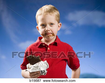 Boy eating chocolate bar with blue sky View Large Photo Image Stock Photo - Boy eating chocolate bar with blue sky. Fotosearch