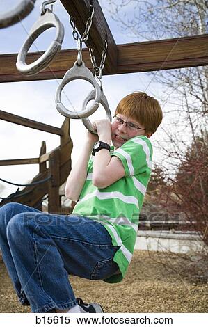 Boy hanging on climbing set at playground outdoors View Large Photo Image Stock Photography - Boy hanging on climbing set at playground outdoors. Fotosearch
