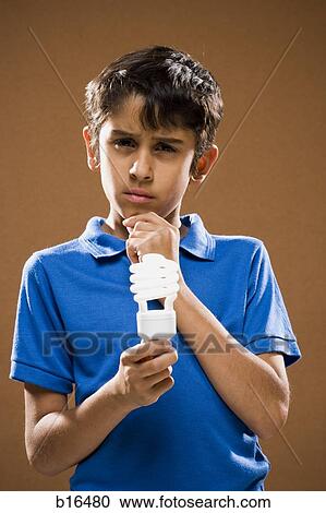Boy holding energy efficient lightbulb thinking View Large Photo Image Stock Image - Boy holding energy efficient lightbulb thinking. Fotosearch