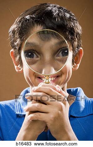 Boy holding magnifying glass to face smiling View Large Photo Image Stock Image - Boy holding magnifying glass to face smiling. Fotosearch