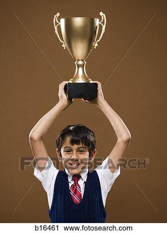 Boy holding trophy cup over head smiling View Large Photo Image Stock Image - Boy holding trophy cup over head smiling. Fotosearch