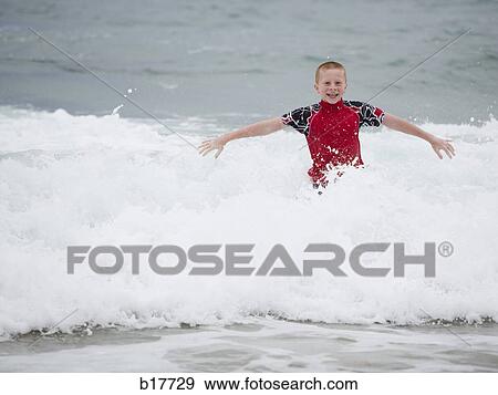 Stock Photo - Boy in water with waves smiling. Fotosearch