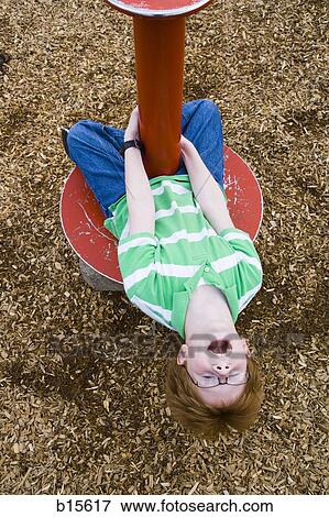 Stock Photo - Boy playing on roundabout outdoors. Fotosearch