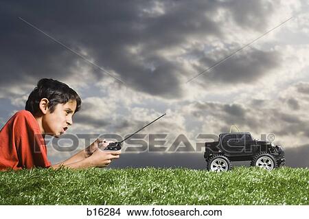 Picture - Boy playing with remote controlled truck outdoors on lawn on cloudy day. Fotosearch