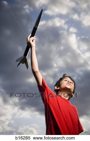 Boy playing with toy rocket outdoors on cloudy day low angle view View Large Photo Image Stock Photography - Boy playing with toy rocket outdoors on cloudy day low angle view. Fotosearch