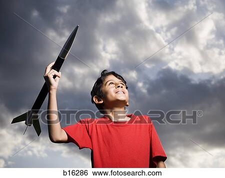Stock Photograph - Boy playing with toy rocket outdoors. Fotosearch
