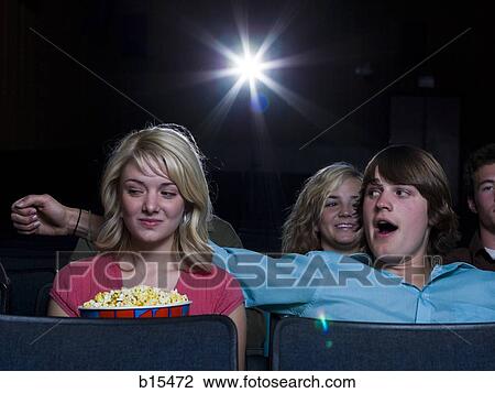 Boy reaching arm out behind girl with popcorn at movie theater View Large Photo Image Stock Image - Boy reaching arm out behind girl with popcorn at movie theater. Fotosearch