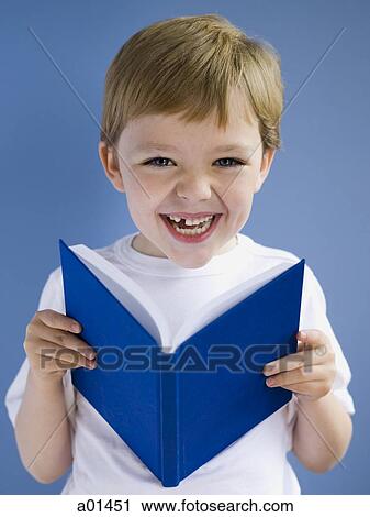 Boy reading hardcover book smiling View Large Photo Image Stock Image - Boy reading hardcover book smiling. Fotosearch
