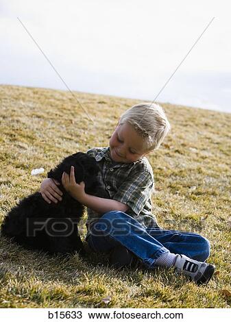 Boy sitting on grass outdoors with puppy View Large Photo Image Stock Image - Boy sitting on grass outdoors with puppy. Fotosearch