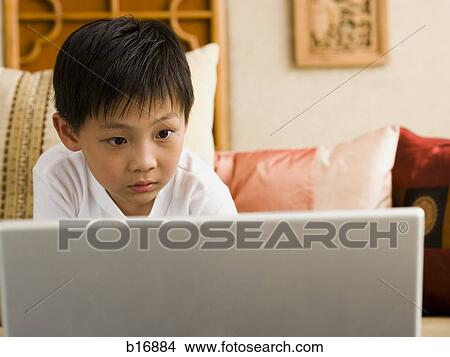 Boy sitting on sofa with laptop View Large Photo Image Picture - Boy sitting on sofa with laptop. Fotosearch