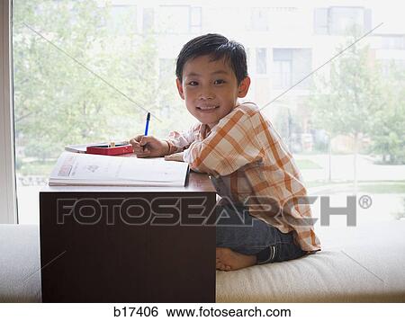 Boy sitting with workbook in front of large window smiling View Large Photo Image Stock Photograph - Boy sitting with workbook in front of large window smiling. Fotosearch