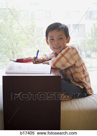 Boy sitting with workbook in front of large window smiling View Large Photo Image Stock Photography - Boy sitting with workbook in front of large window smiling. Fotosearch