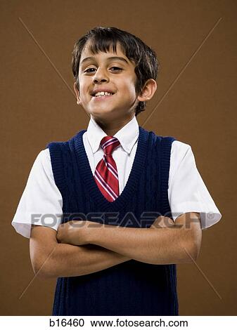 Stock Image - Boy standing with arms crossed smiling. Fotosearch